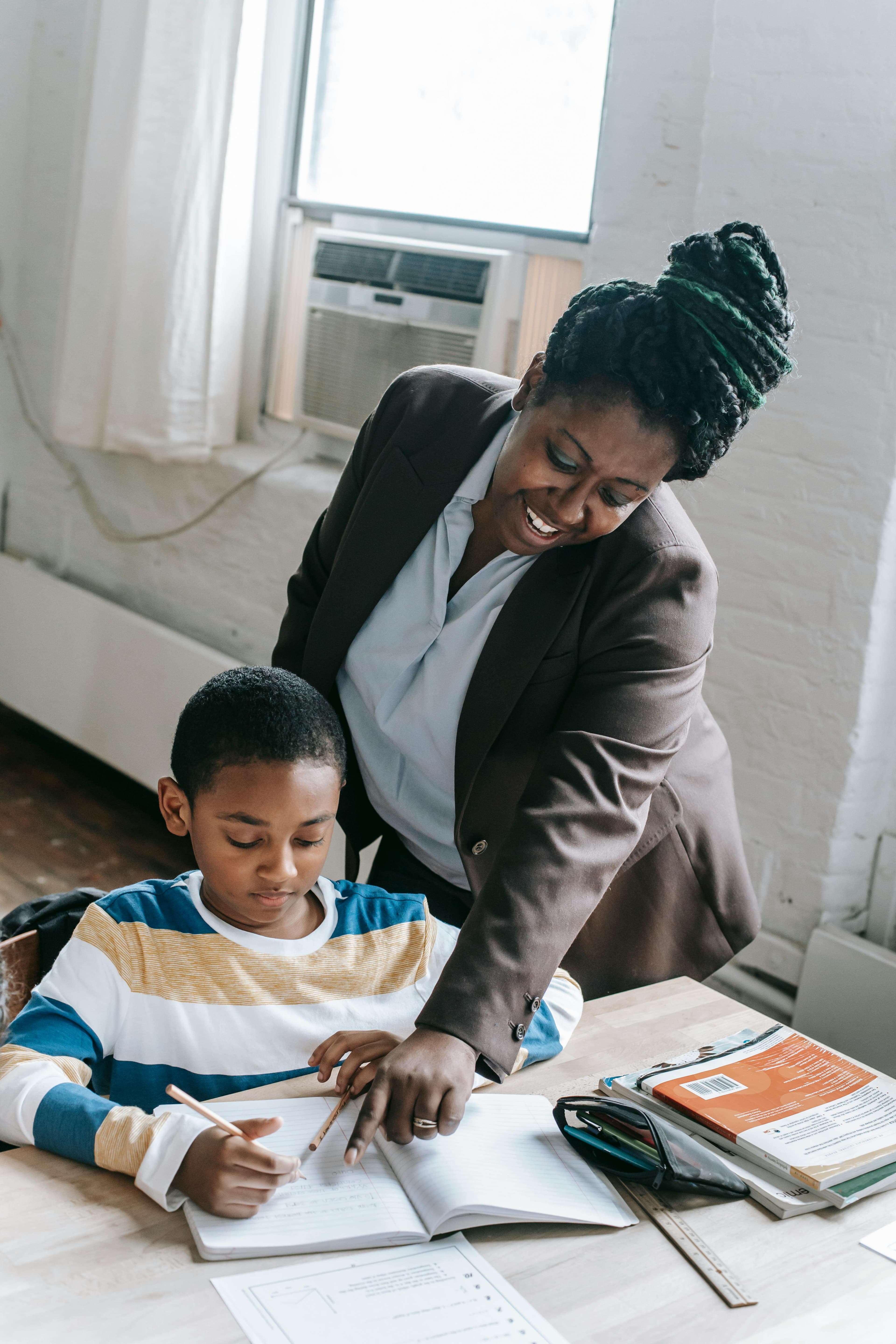 A teacher working closely with a student at a desk.